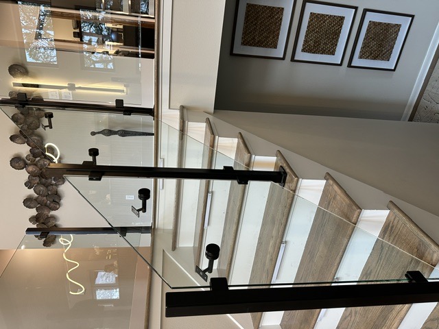 Glass stair railing with black posts in a modern home by West Little Rock Glass, serving Maumelle
