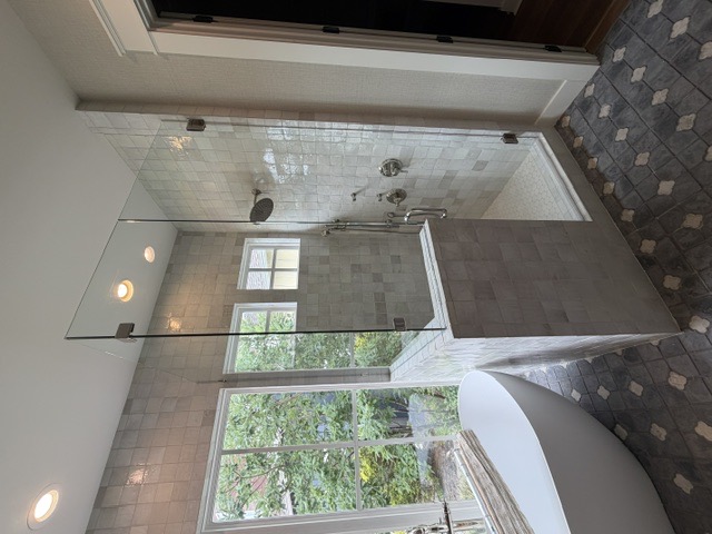 Frameless glass shower panel beside a freestanding tub by West Little Rock Glass, a common Greers Ferry lake-home upgrade