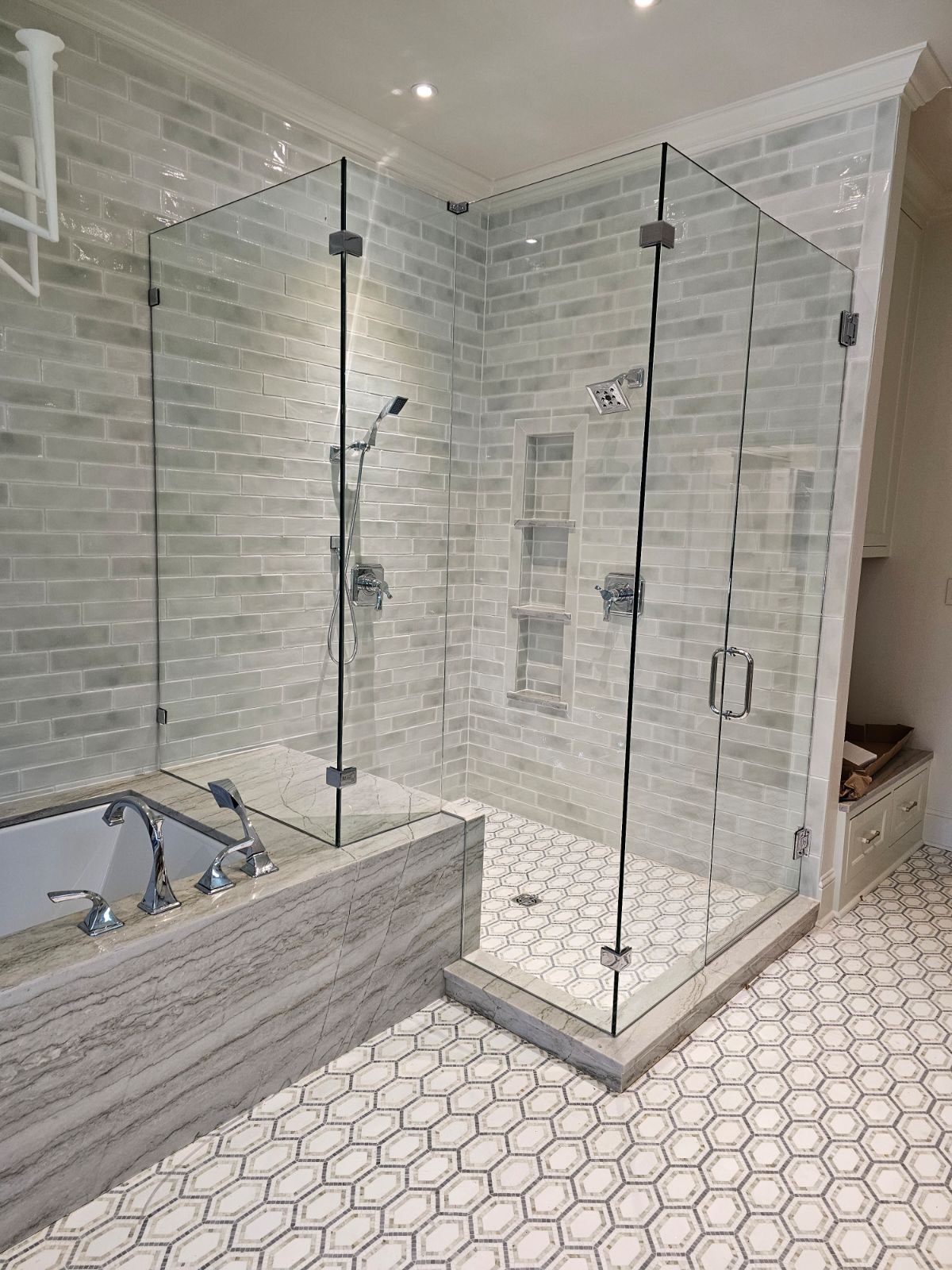 Frameless corner shower over sage subway tile with hex mosaic floor by West Little Rock Glass